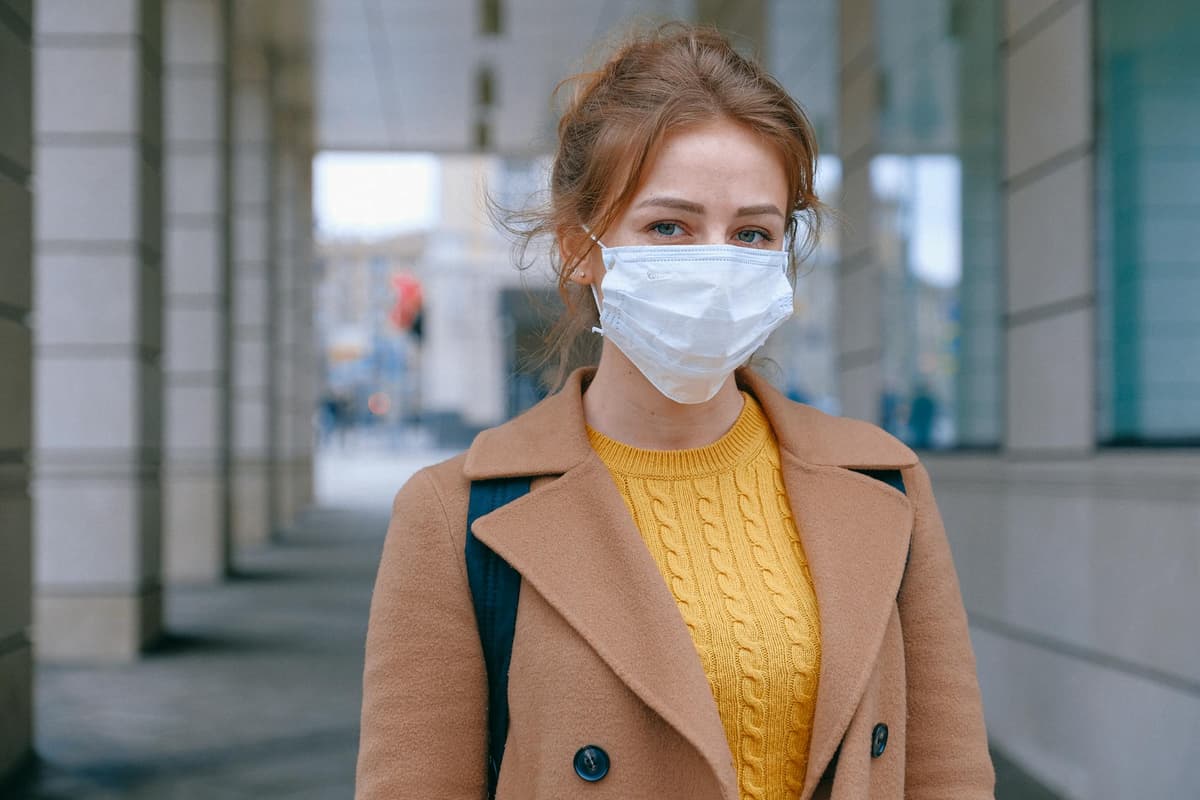http://Woman stands outside wearing medical mask