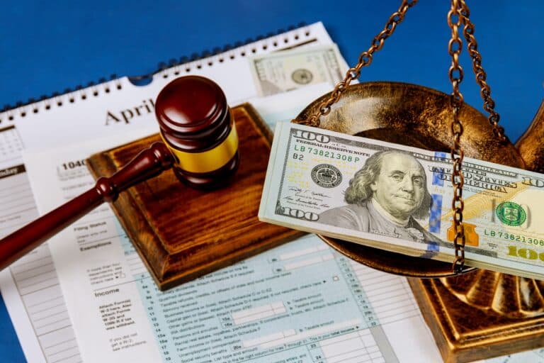 Hundred US dollar bills on a table scales of justice, gavel IRS form. 1040 U.S tax forms calendar while pages April of the deadline time tax season