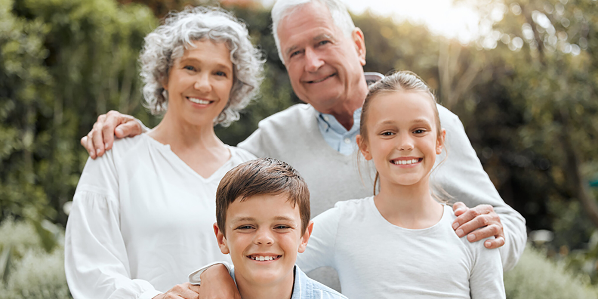 Two grandparents pose happily with their two grandkids.