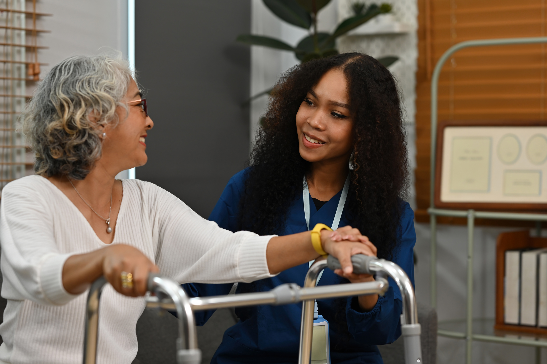 An African-Asian nursing assistant supports a senior woman