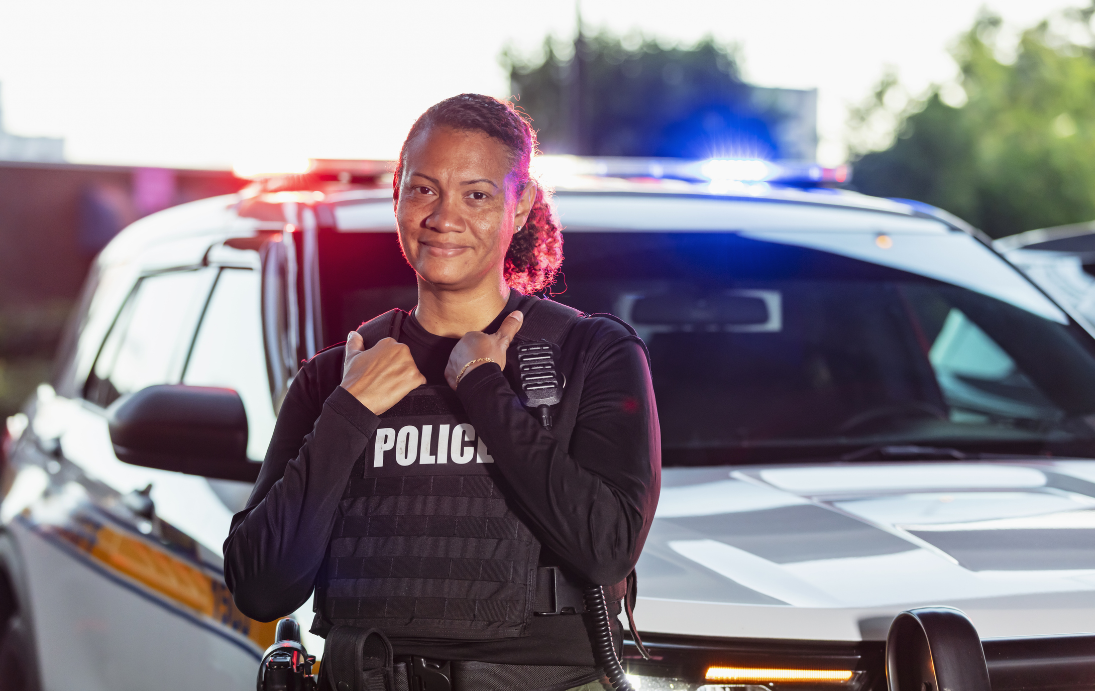 Portrait of a mature policewoman standing outdoors in front of her police car