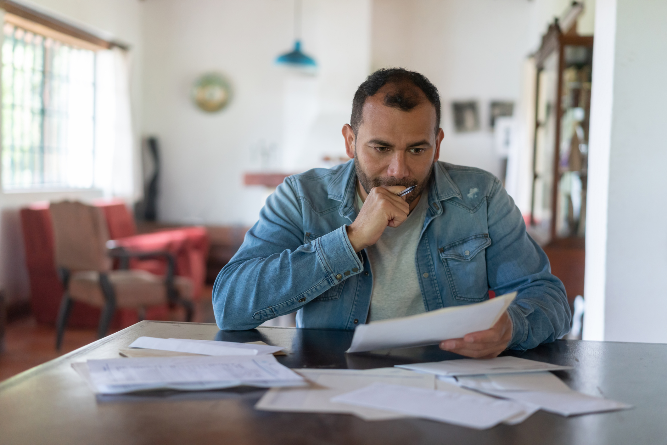 Man sits at table looking at bills and paperwork