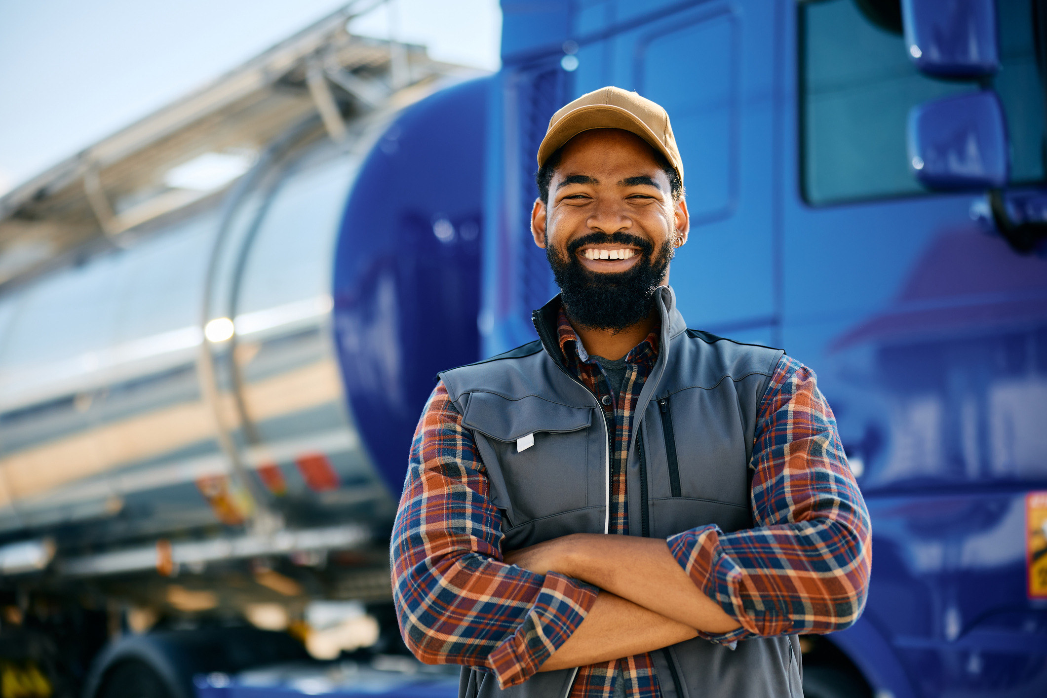 Happy African American truck driver with arms crossed looking at camera.