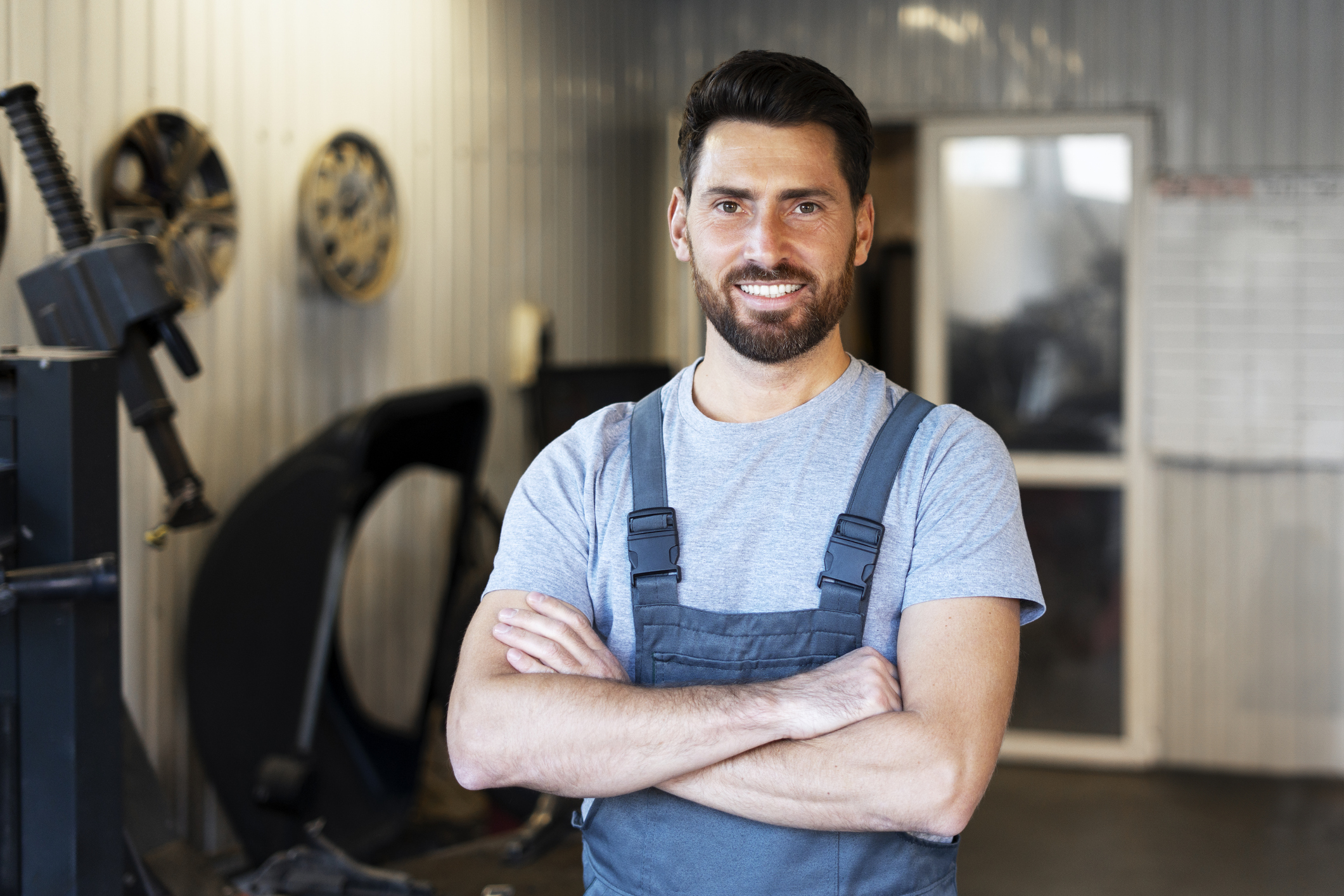 Mechanic smiling with crossed arms in auto repair shop