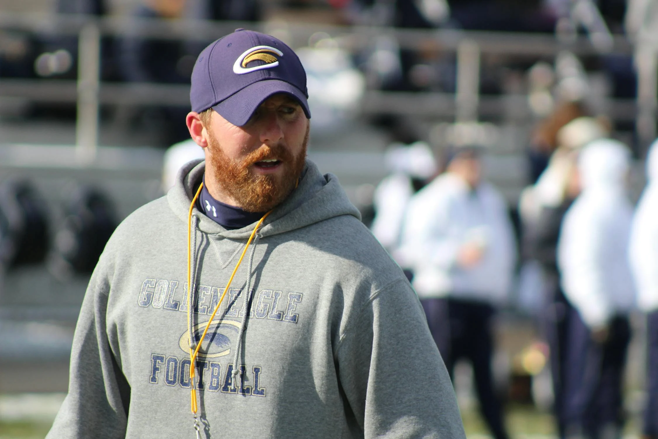 College football coach stands in field