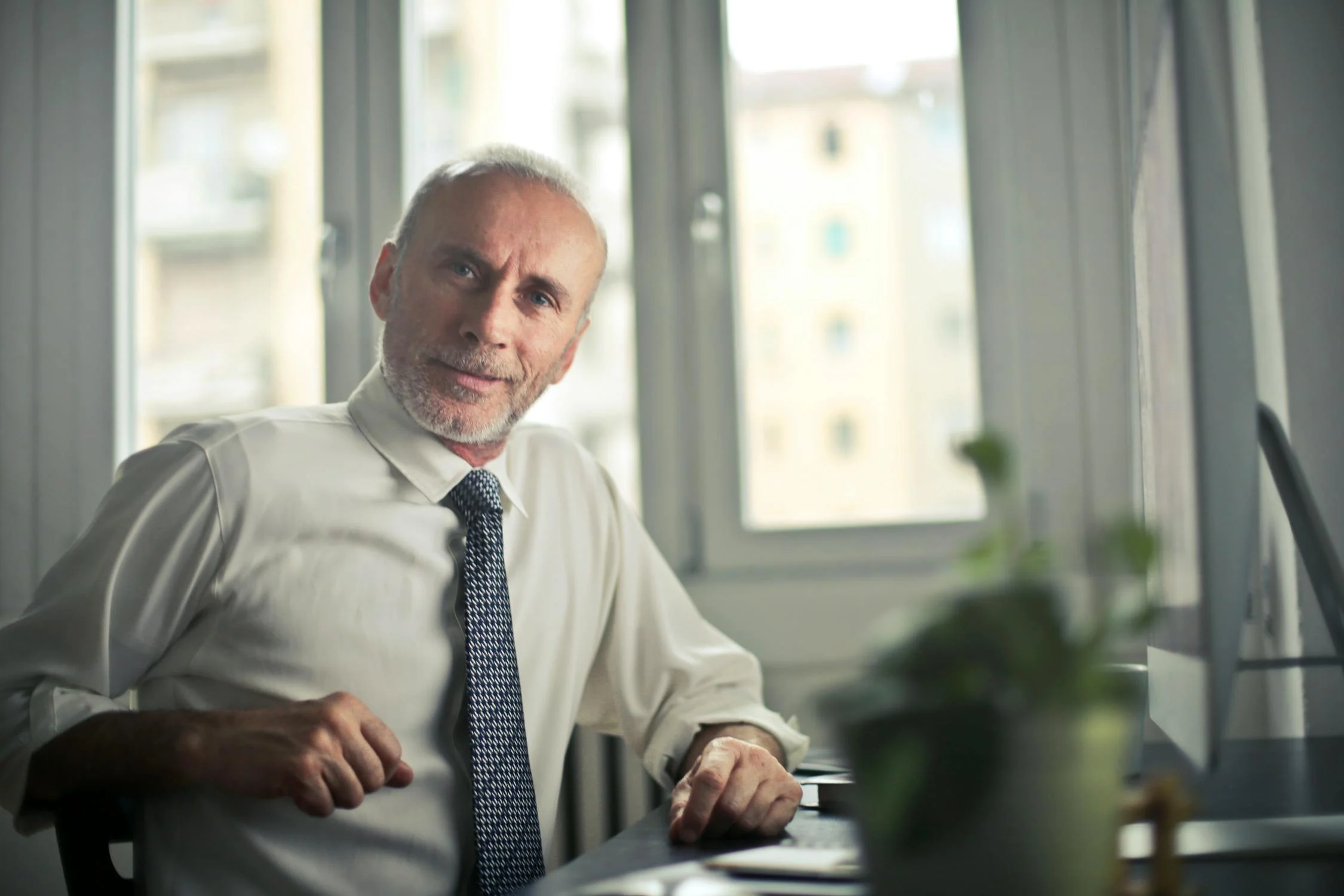 Older professional man sits at desk