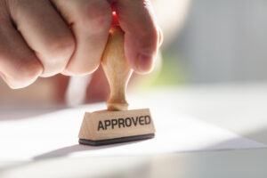 Businessman stamping approved stamp on document in meeting