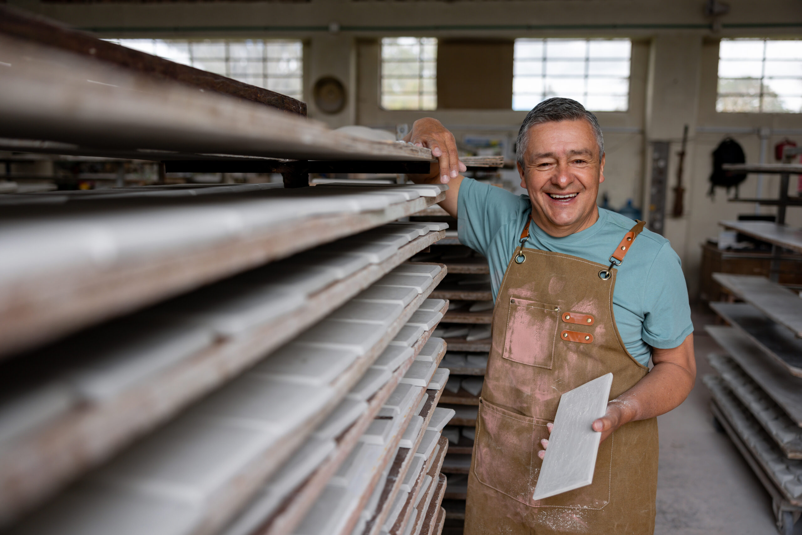 Older tile maker stands happily in workshop