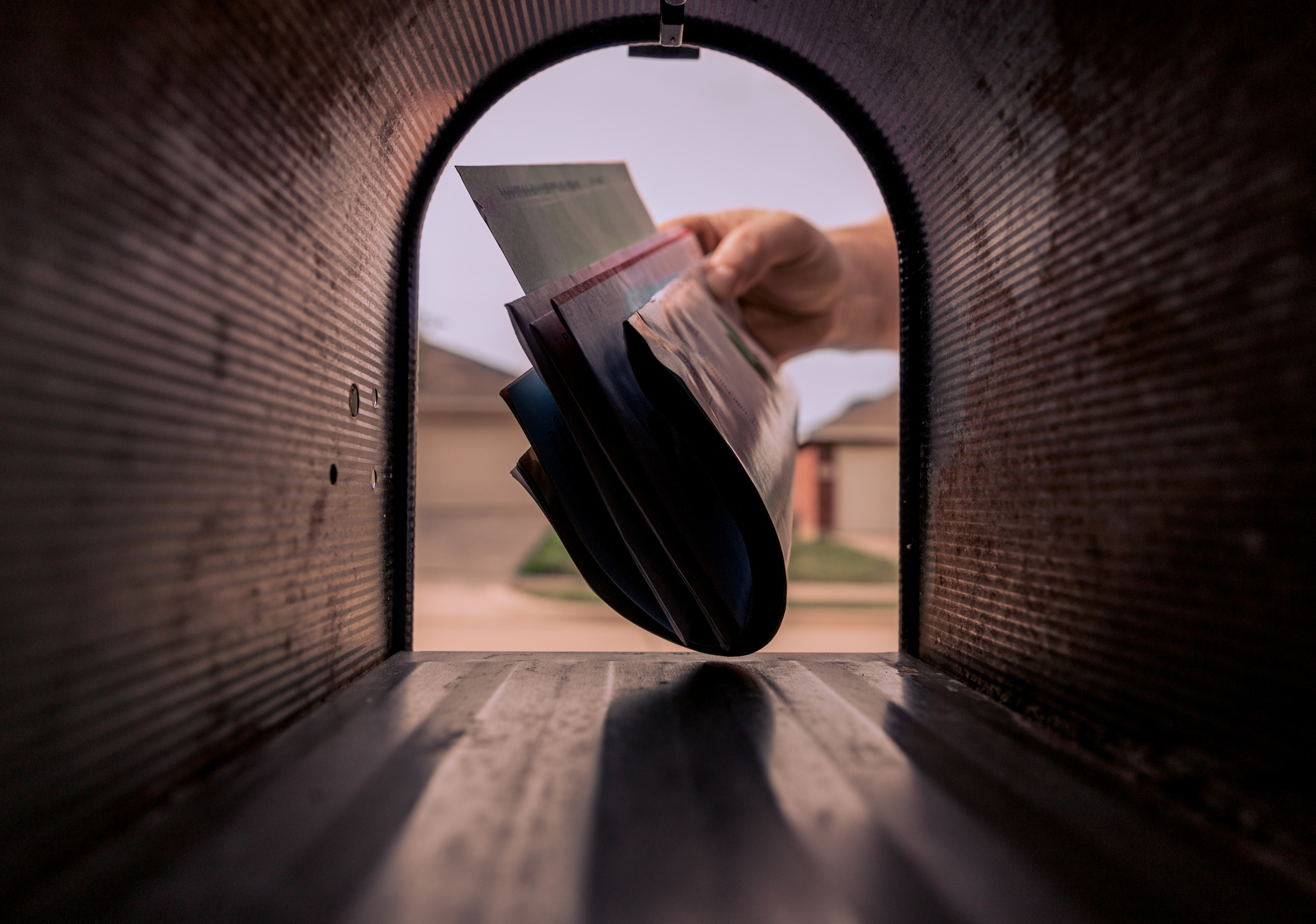 A hand placing mail in a mailbox.