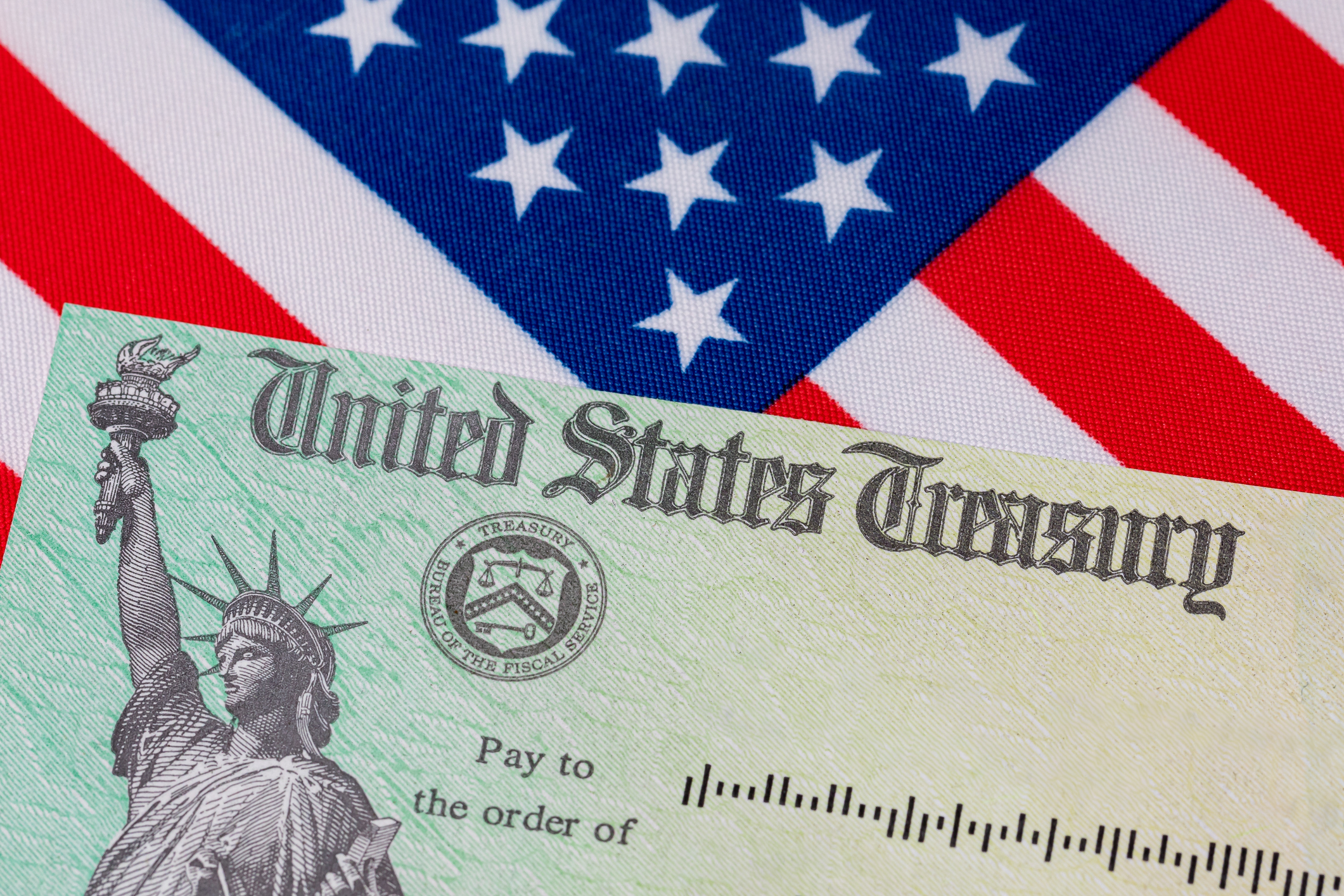 United States Treasury check and American flag. Concept of stimulus payment, tax refund.