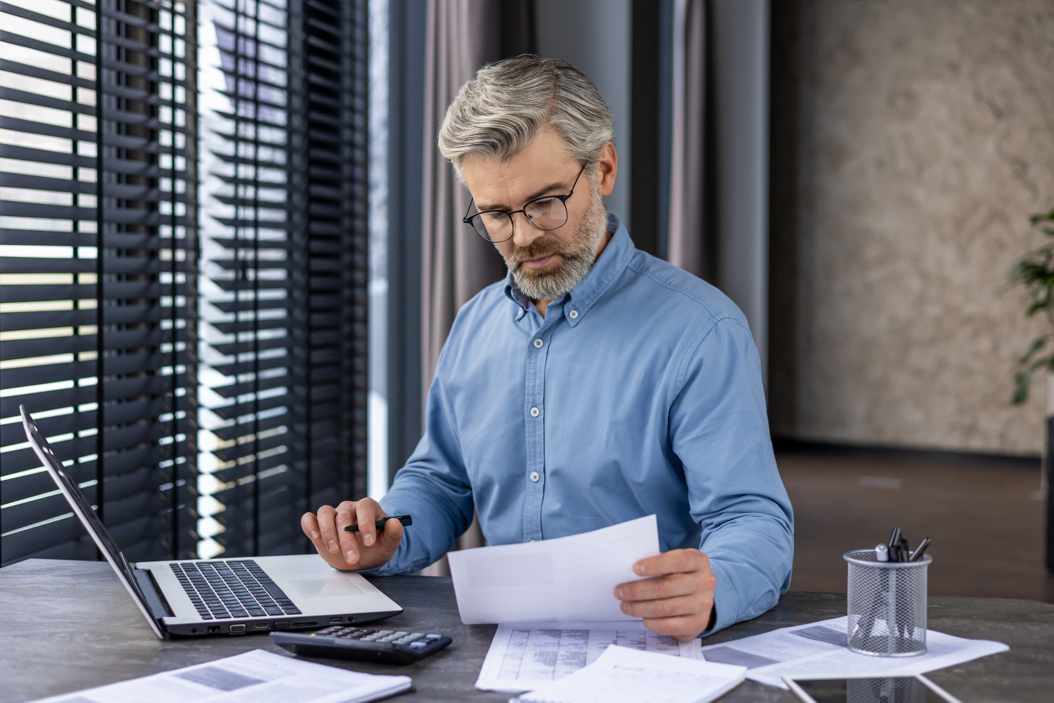 Mature business owner man reviews paperwork and documents.