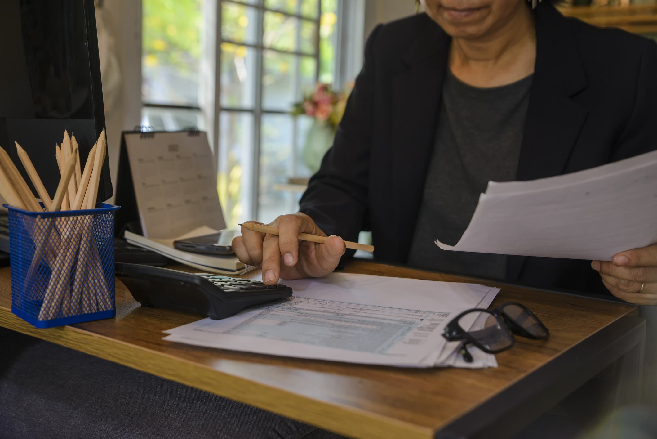 Budget and Tax planning concept, Accountant Hand is calculating company annual tax and using calculator. Personal income tax form for who have income under US law, season to pay tax.
