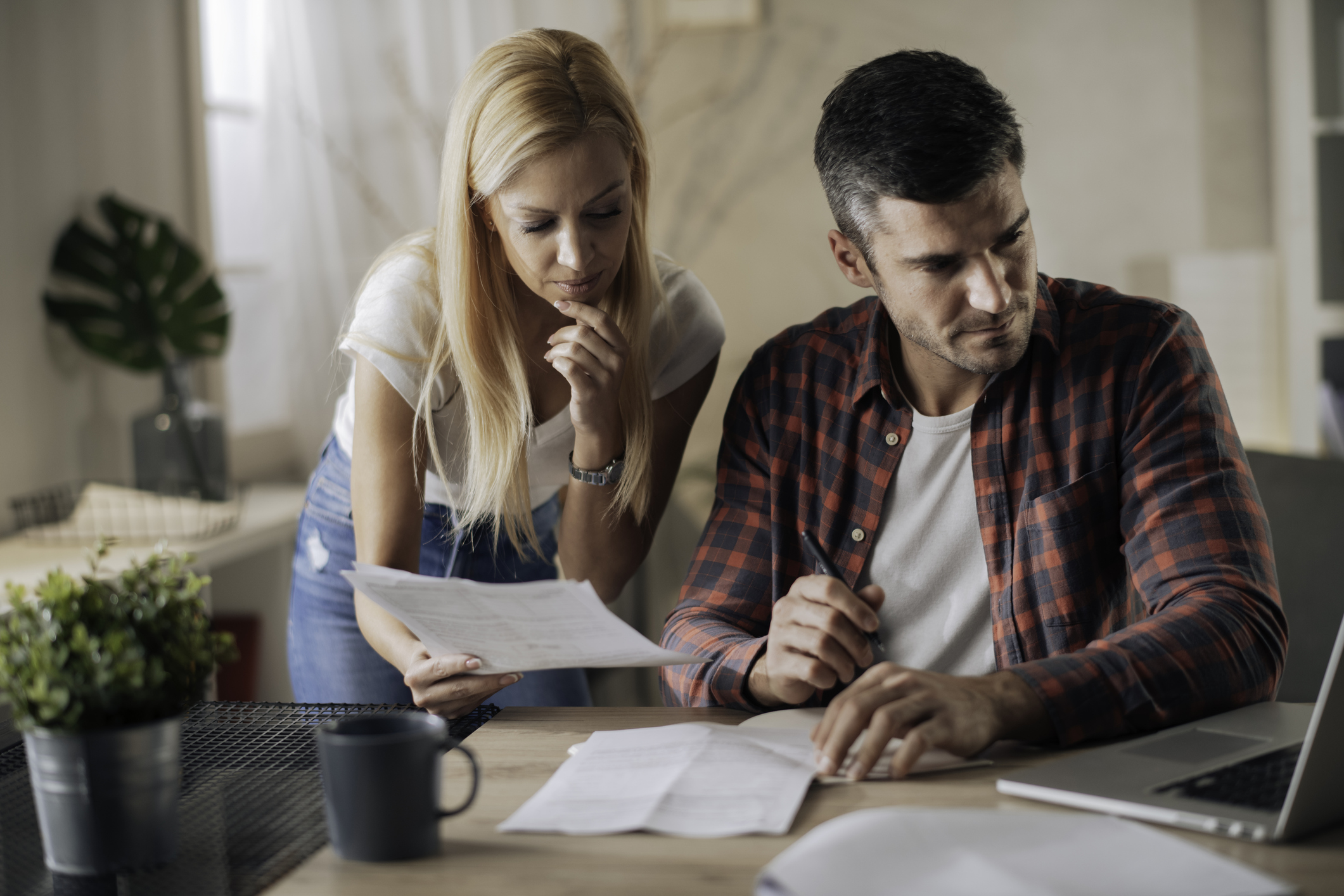 Worried young couple applying for IRS CNC status online in computer app.