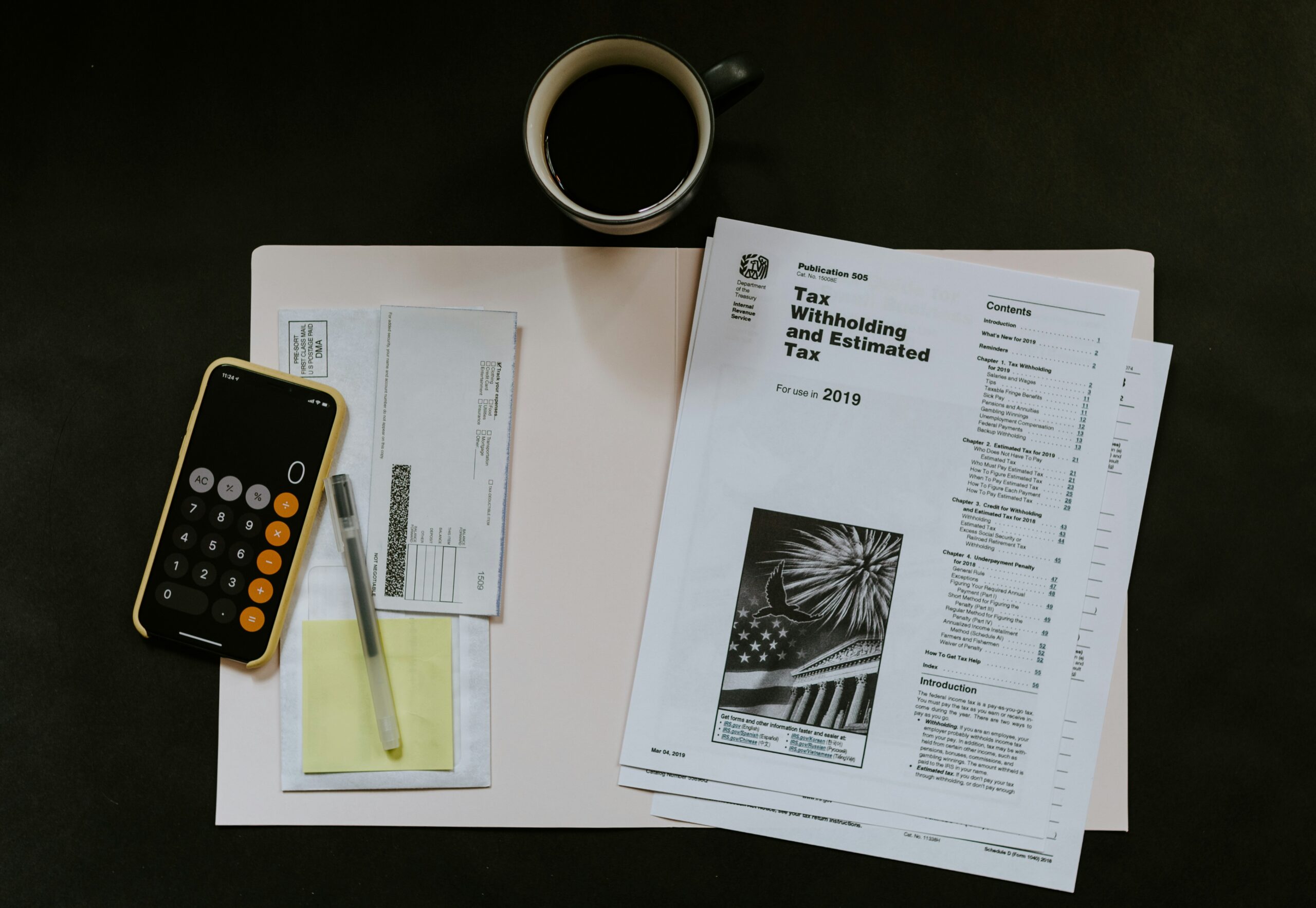 Tax paperwork, a calculator, and coffee mug are laid out on a desk to set up an IRS payment plan or installment agreement.